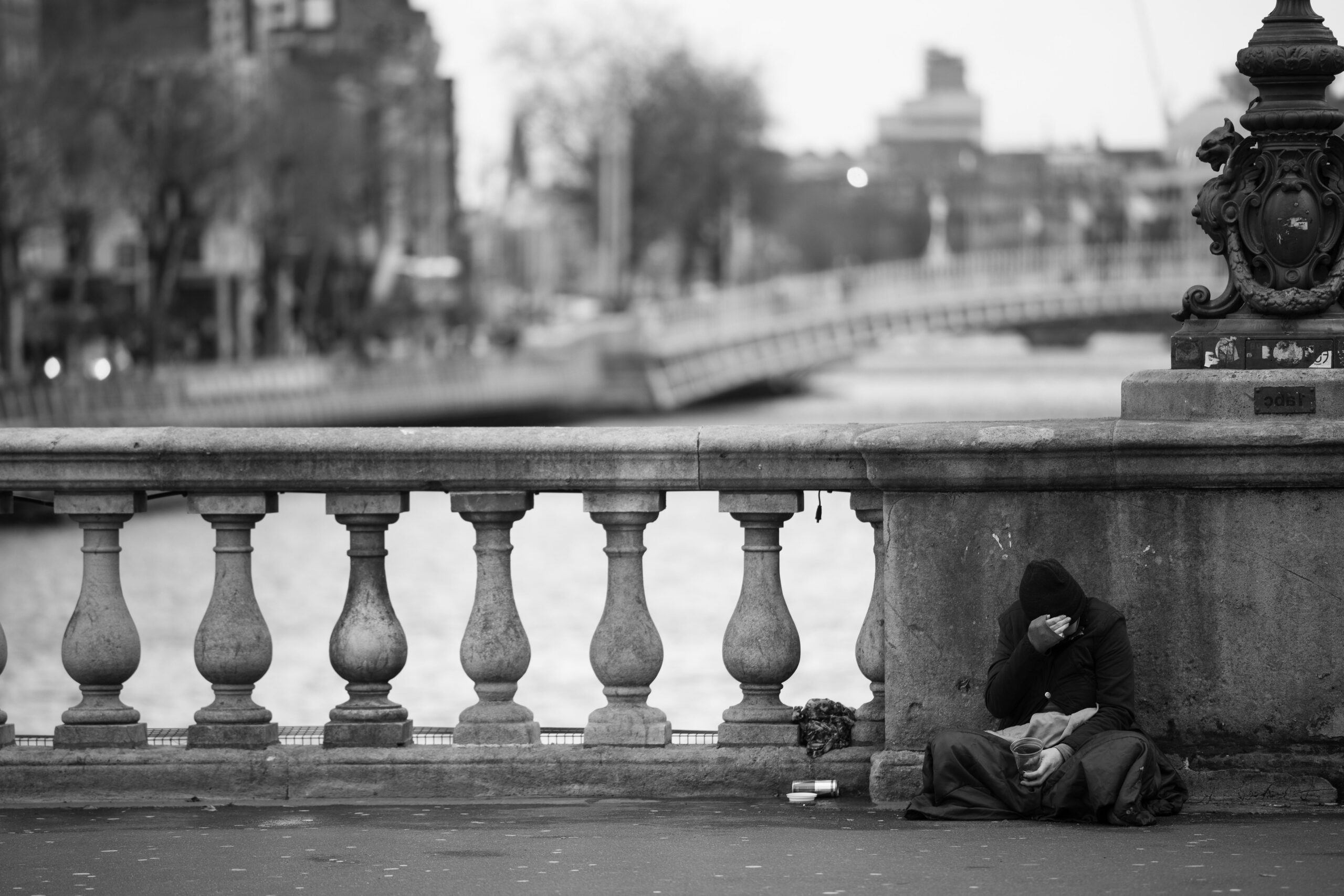 Man on bridge in the cold sitting on the floor
