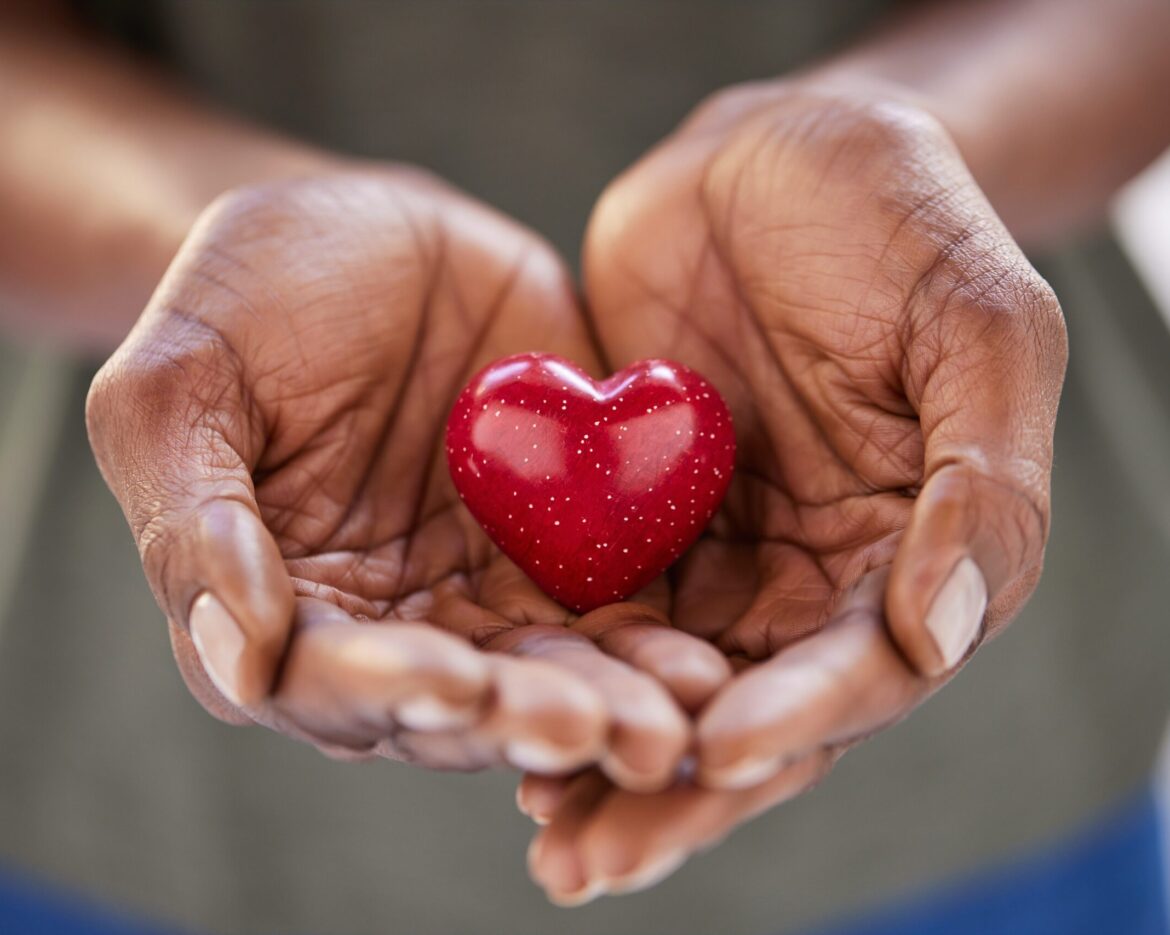 Close up of african woman hands holding red heart in solidarity